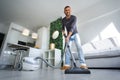 Young happy man vacuuming at home. Man cleaning house with vacuum cleaner. House keeping Royalty Free Stock Photo