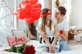 Young happy man makes an offer of hands and hearts to his beloved girl. Closing her eyes with hand, he holds in front of her a red Royalty Free Stock Photo