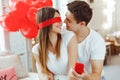 Young happy man makes an offer of hands and hearts to his beloved girl. Closing her eyes with hand, he holds in front of her a red Royalty Free Stock Photo