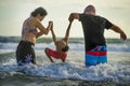 Young happy mixed ethnicity couple Caucasian man and Asian Indonesian woman playing at tropical beach with little son the parents