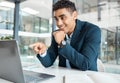 Young happy mixed race businessman pointing a finger while working on a laptop alone at work. Hispanic male Royalty Free Stock Photo