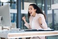 Young happy mixed race businesswoman cheering with joy using a desktop computer in an office. One cheerful hispanic Royalty Free Stock Photo