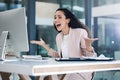 Young happy mixed race businesswoman looking shocked and amazed using a desktop computer in an office. One cheerful Royalty Free Stock Photo