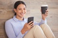 Young happy mixed race businesswoman using social media on her phone while drinking a cup of coffee on a break sitting Royalty Free Stock Photo