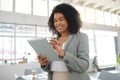 Young happy mixed race businesswoman working on a digital tablet in an office. One cheerful hispanic female boss with a Royalty Free Stock Photo