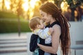 Young happy mother with baby son in ergo backpack walking in Sunny summer day. Concept of the joy of motherhood Royalty Free Stock Photo