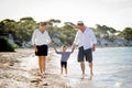 Young happy mother and father walking on beach in family vacation concept Royalty Free Stock Photo