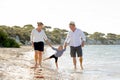 Young happy mother and father walking with little daughter on beach in family vacation concept Royalty Free Stock Photo