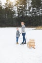 Young happy mother and her son enjoying a sledge ride in a beautiful snowy winter forest. Wooden sledge with present Royalty Free Stock Photo