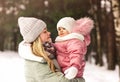 Young happy mother in winter holds her little daughter in her arms and looks at her. Family portrait. Motherhood and childhood Royalty Free Stock Photo