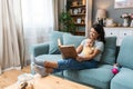 Young happy mother reading a fairytale story book to her baby. Mommy and kid sitting on sofa at home enjoying in imagination.