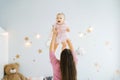 A young happy mother throws her charming daughter in the nursery. The concept of small healthy fun children Royalty Free Stock Photo