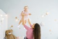 A young happy mother throws her charming daughter in the nursery. The concept of small healthy fun children Royalty Free Stock Photo