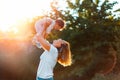 Young happy mother throws up baby in the sky, summer outdoors. Side view. Concept of happy childhood Royalty Free Stock Photo