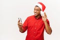 Young happy multiracial man in santa hat waving hand making video call on a smart phone Royalty Free Stock Photo