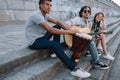 Young and happy multiracial street musicians band sitting with instruments