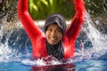 Young happy muslim woman playing with water excited in resort swimming pool splashing and having fun wearing traditional islam Royalty Free Stock Photo