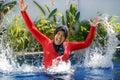 Young happy muslim woman playing with water excited in resort swimming pool splashing and having fun wearing traditional islam Royalty Free Stock Photo