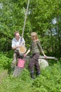 Young happy pair at a well,pours water in a bucket Royalty Free Stock Photo