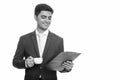 Young happy Persian businessman reading clipboard while holding coffee cup Royalty Free Stock Photo