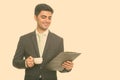 Young happy Persian businessman reading clipboard while holding coffee cup Royalty Free Stock Photo