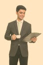 Young happy Persian businessman reading clipboard while holding coffee cup Royalty Free Stock Photo