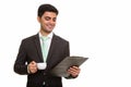 Young happy Persian businessman reading clipboard while holding Royalty Free Stock Photo