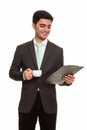 Young happy Persian businessman reading clipboard while holding Royalty Free Stock Photo