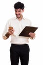 Young happy Persian businessman smiling and holding clipboard wh Royalty Free Stock Photo