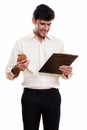 Young happy Persian businessman smiling and reading on clipboard Royalty Free Stock Photo