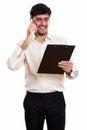 Young happy Persian businessman smiling and reading on clipboard Royalty Free Stock Photo