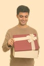 Young happy Persian man opening gift box ready for Valentine`s day Royalty Free Stock Photo