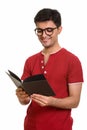 Young happy Persian man reading book while smiling Royalty Free Stock Photo