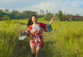 Young happy and playful Asian Chinese woman in beautiful dress having fun enjoying holidays excursion on grass tropical field smil Royalty Free Stock Photo