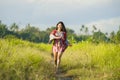 Young happy and playful Asian Chinese woman in beautiful dress having fun enjoying holidays excursion on grass tropical field smil Royalty Free Stock Photo