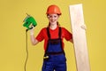 Young happy positive carpenter woman working with fretsaw, holding wooden panel. Royalty Free Stock Photo