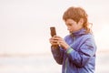 young happy preeteen boy looking at smth on phone screen, outdoor portrait