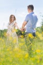 Young happy pregnant couple in love holding hands, relaxing in meadow. Royalty Free Stock Photo