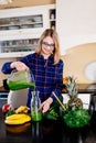 Young happy pregnant woman pouring green smoothie to glass cup Royalty Free Stock Photo