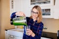 Young happy pregnant woman pouring green smoothie to glass cup Royalty Free Stock Photo