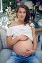 Young happy pregnant woman sitting on sofa Royalty Free Stock Photo