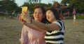 Young happy and pretty Asian Chinese girl on the beach taking selfie photo with her mother, a 60s mature woman , enjoying Summer Royalty Free Stock Photo