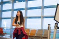 Young happy and pretty Asian Chinese tourist woman pulling suitcase trolley in airport departure gate walking and holding boarding