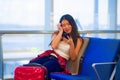 Young happy and pretty Asian Chinese tourist woman sitting at airport departure boarding gate waiting for flight using internet on Royalty Free Stock Photo