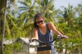 Young happy and pretty Asian Chinese woman riding bike in Vietnam or Thailand tropical jungle forest with palm trees smiling relax Royalty Free Stock Photo