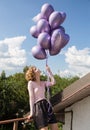 Young happy pretty girl 17-18 years old with a bunch of purple helium balloons