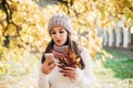 Young happy pretty women using phone in park.Bright sunny autumn day.Wearing knitted clothes Royalty Free Stock Photo