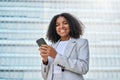 Young happy African American business woman holding phone standing on street. Royalty Free Stock Photo