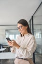 Happy Asian business woman worker using mobile phone in office, vertical. Royalty Free Stock Photo