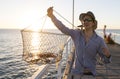 Proud attractive fisherman showing fish and crabs basket net captures smiling at sea dock sunset in man fishing as weekend hobby Royalty Free Stock Photo